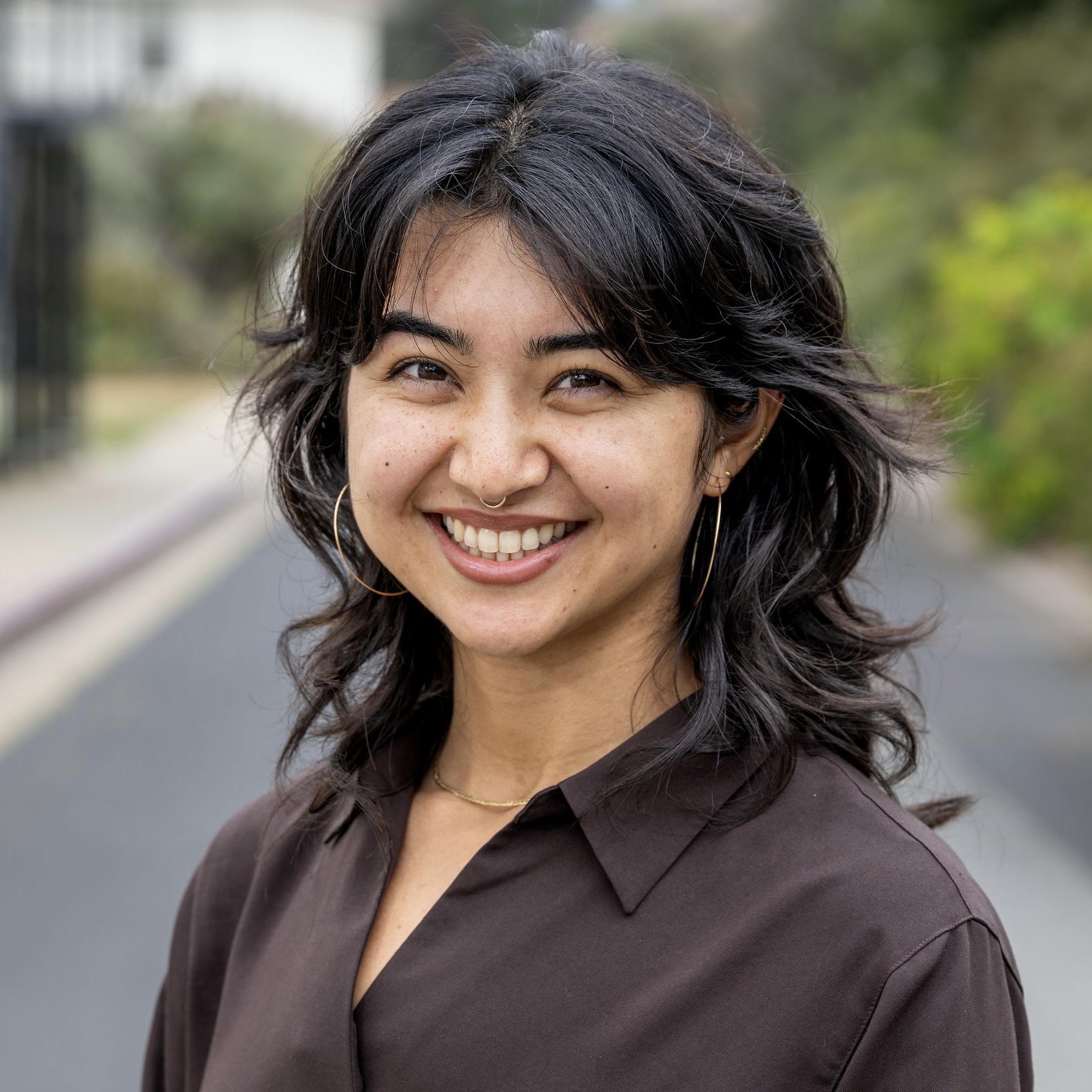 Anna smiles at the camera in a dark brown blouse.