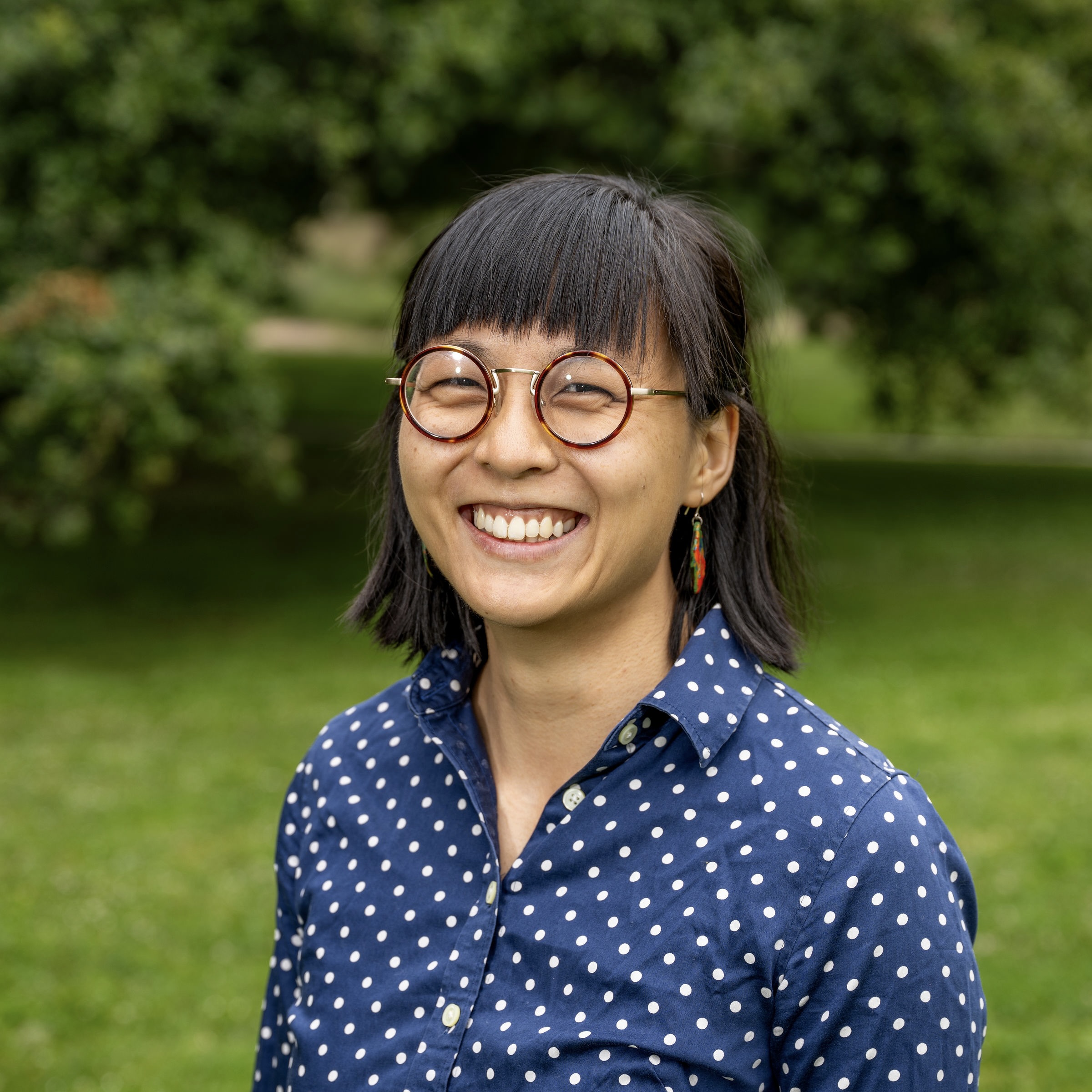 Alicia smiles at the camera in a polkadot, dark blue collared shirt.