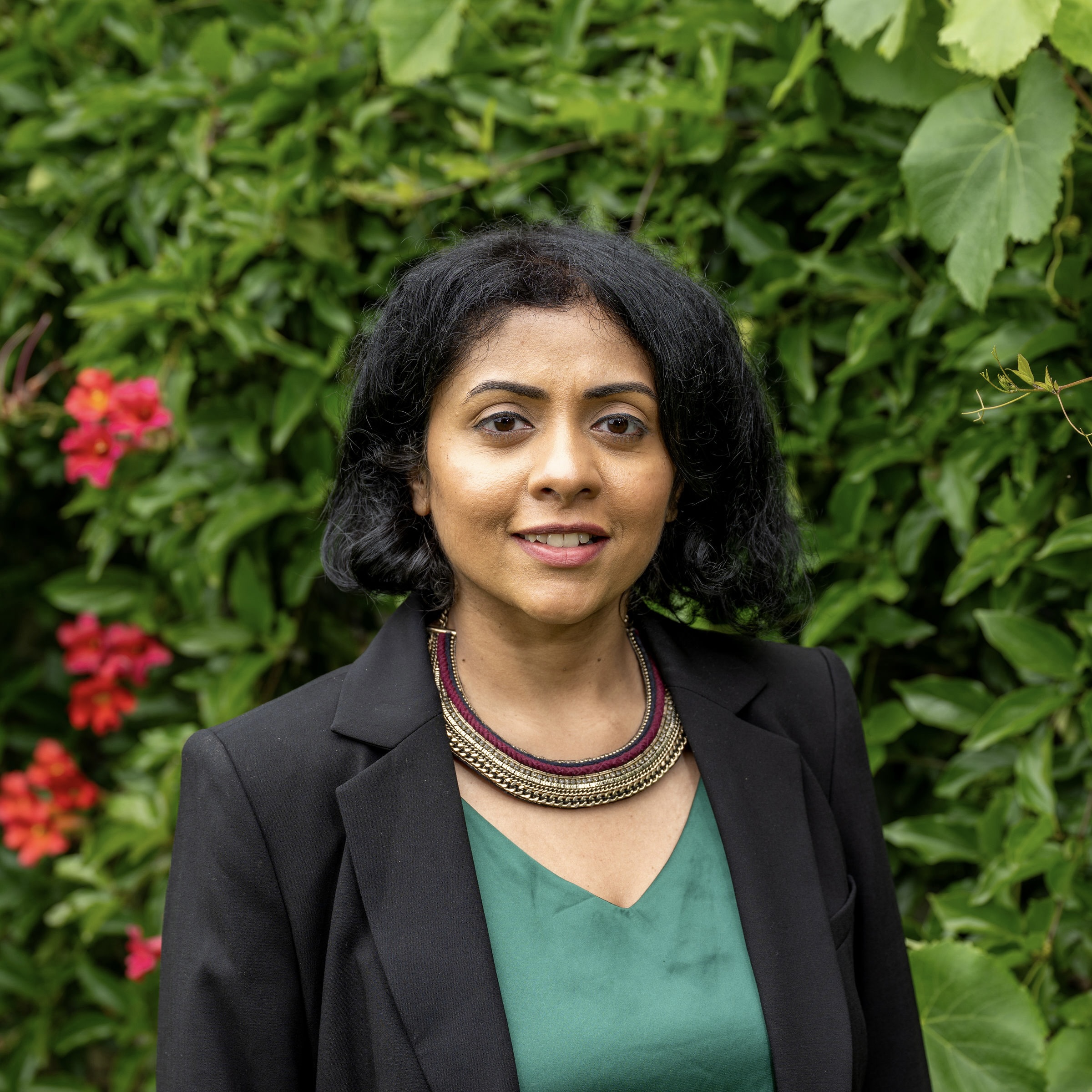 Venita smiles at the camera in a dark green blouse and black suit jacket.