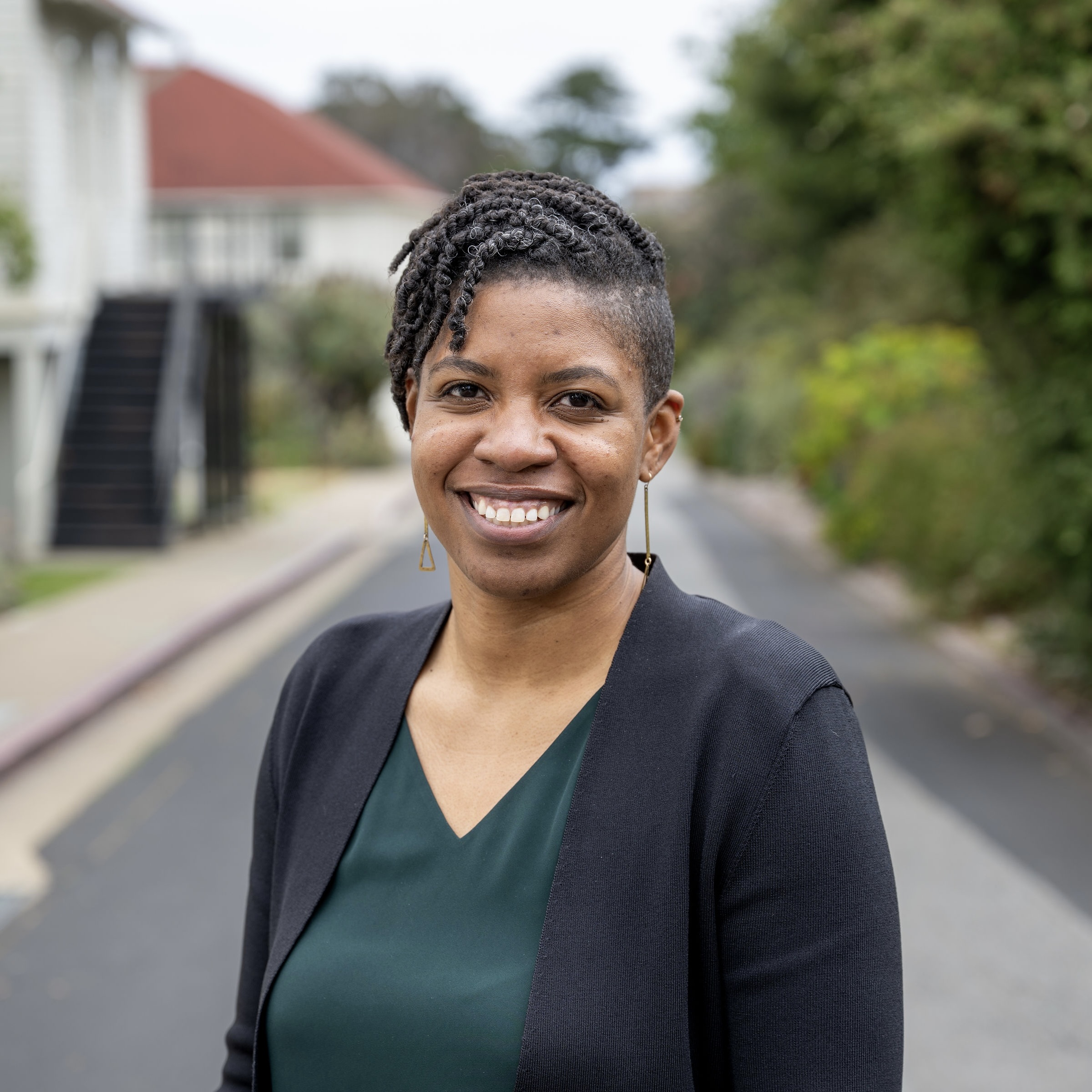 Rebecca smiles at the camera in a dark green blouse and black suit jacket.
