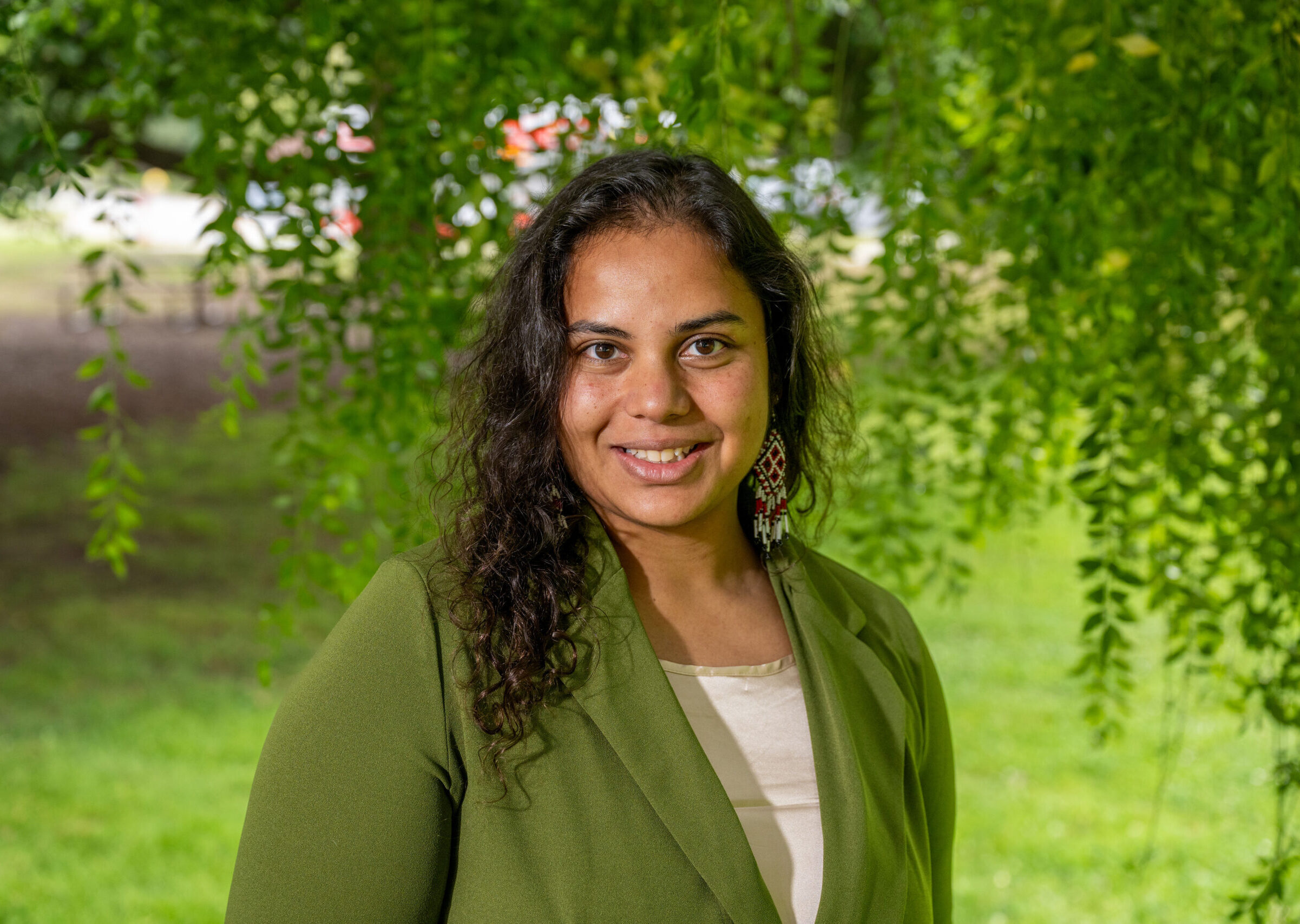 Manisha smiles looking directly at the camera in a bright green suit jacket and white blouse.