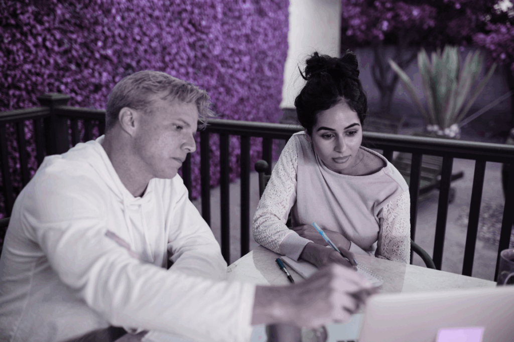 Two people sitting at a desk looking at a laptop.