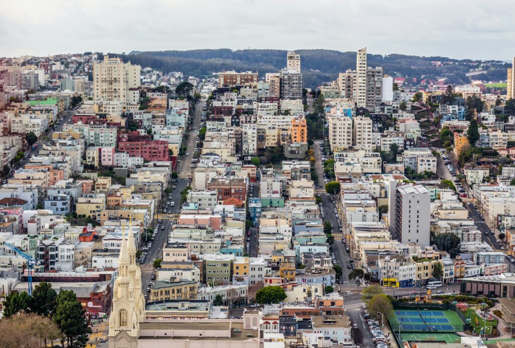 A shot of a sloping hill covered in buildings and trees.