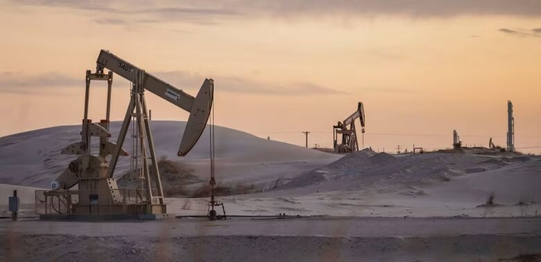 An oil rig pumps oil on desolate land at dusk.