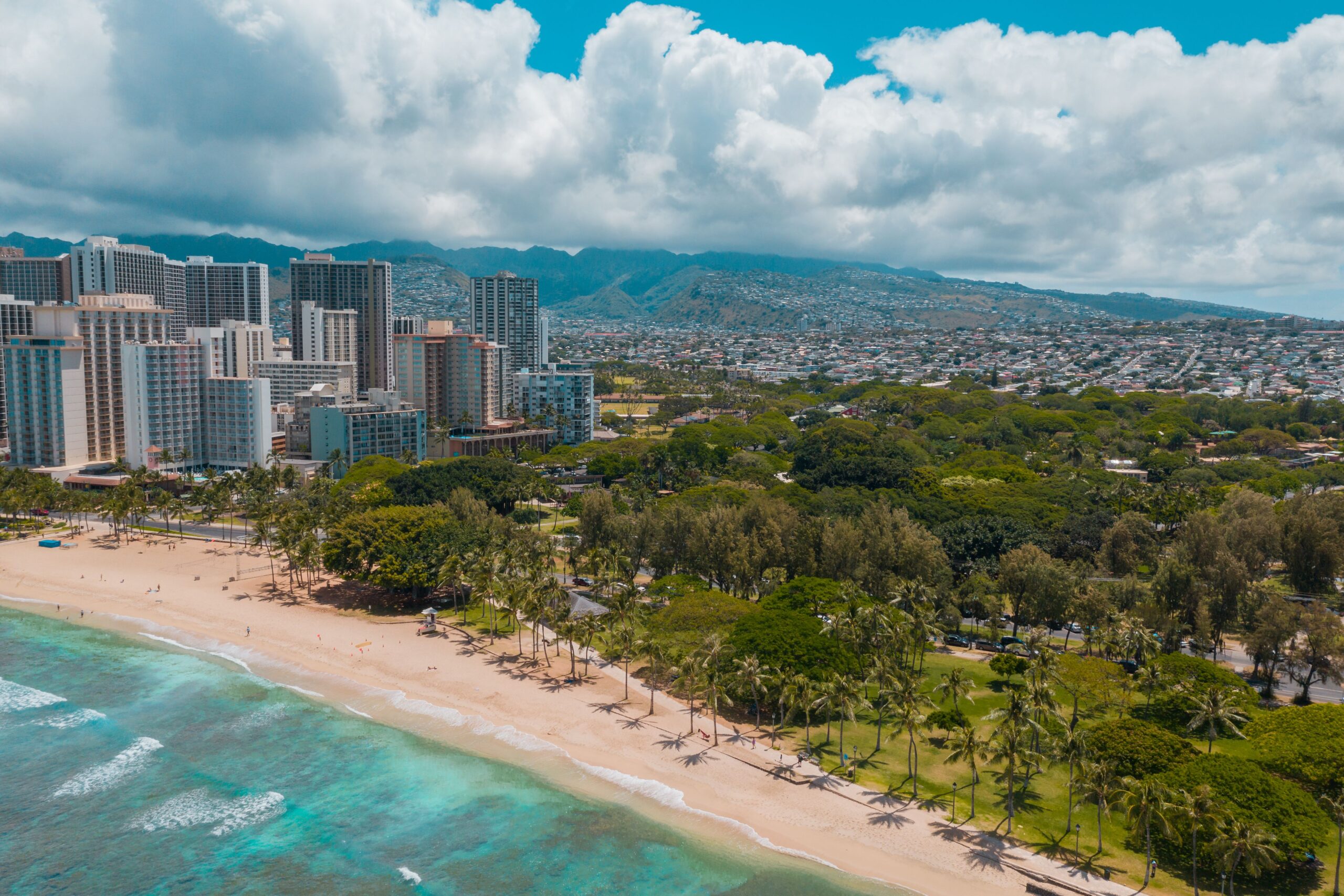 Aerial view of the coast in Hawai'i with sky scrapers in the background.
