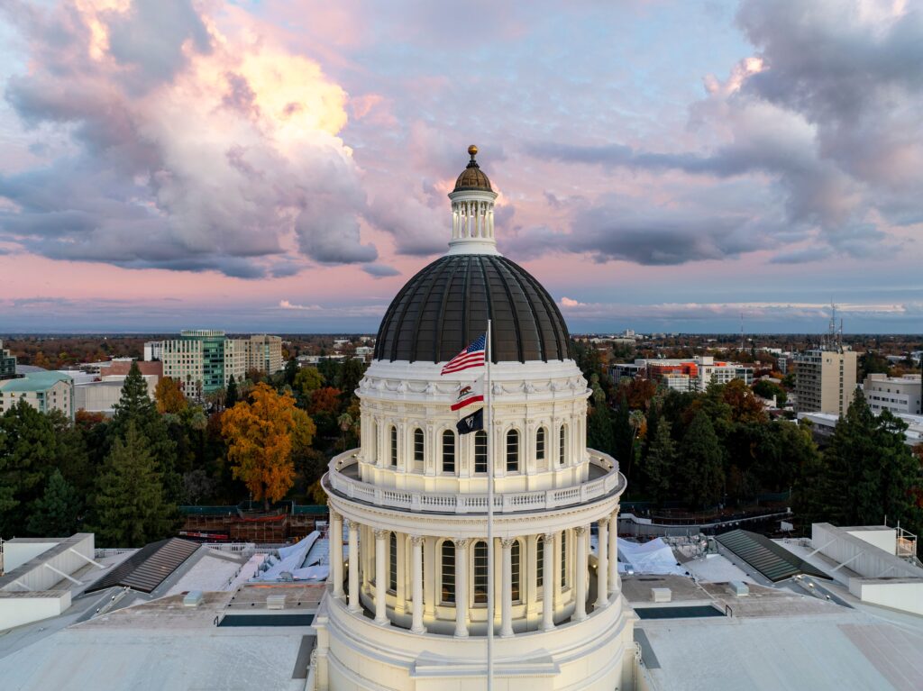 A stunning aerial view of the California State Capitol Dome under a colorful sky at dusk.